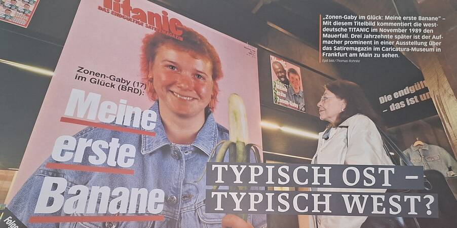 Eine Frau betrachtet ein Plakat mit der Aufschrift "Meine erste Banane" aus einem ehemaligen deutschen Satire-Magazin im Caricatura-Museum, das sich mit dem Mauerfall beschäftigt.