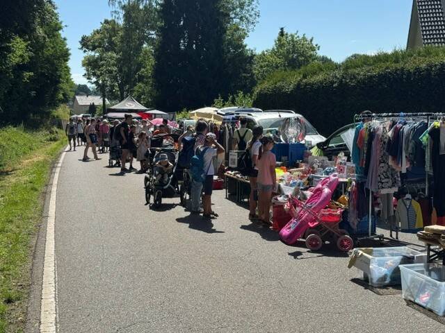 Eine Gruppe von Menschen schlendert an Ständen vorbei, die entlang einer Straße aufgestellt sind und verschiedene Waren zum Verkauf anbieten.