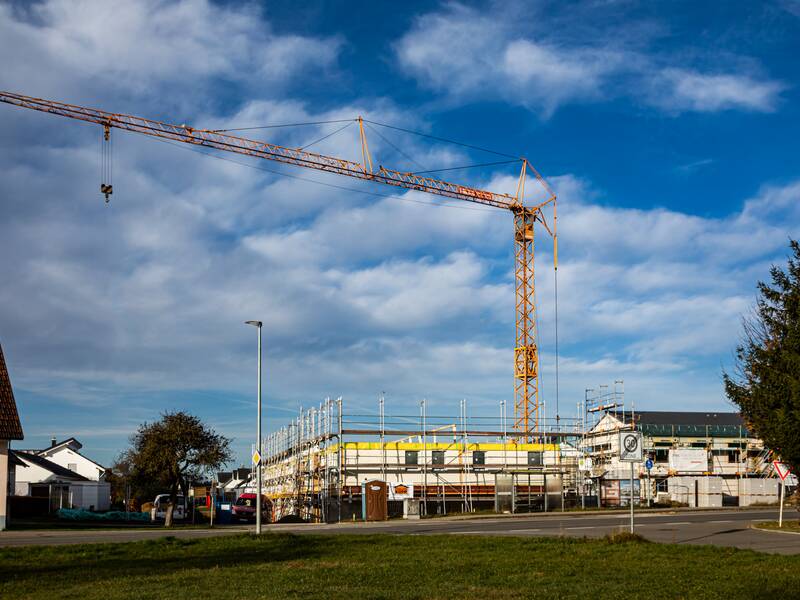 Ein gelber Baukran bei einer Baustelle für ein Haus.